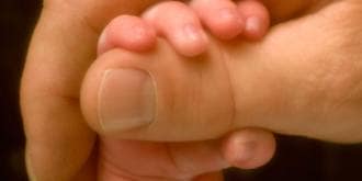 Baby holding fathers finger