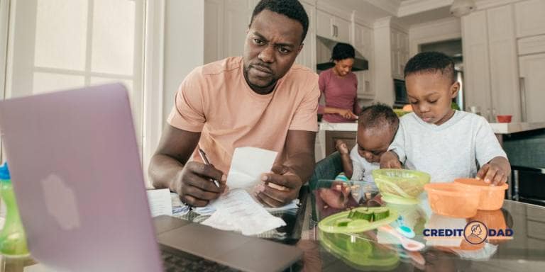 A father budgeting with bills and a laptop while his children eat at the table, showcasing family financial planning.